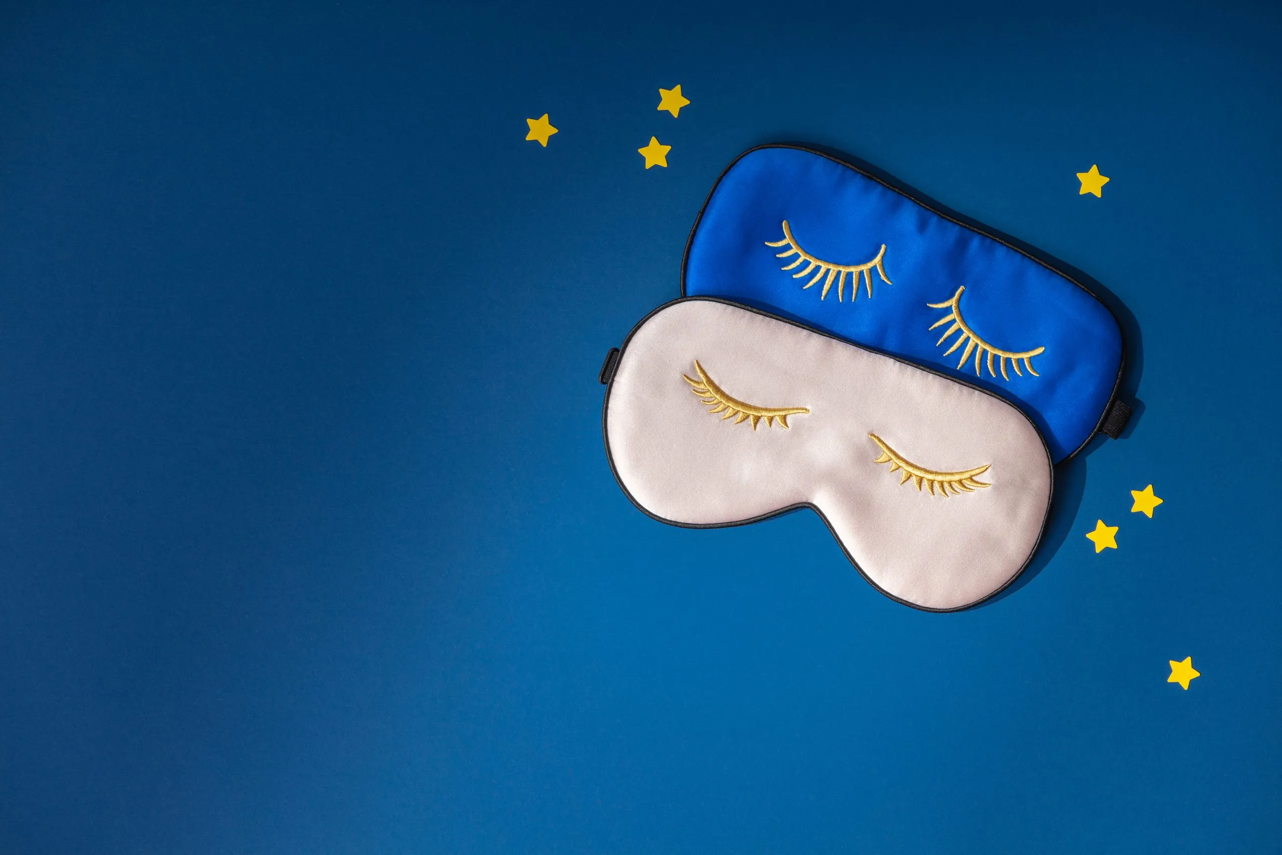 Deux masques de sommeil et des étoiles en papier sur fond bleu nuit